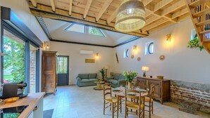 Amplia sala de estar con mesa de comedor, sofás y zona de cocina con cafetera.