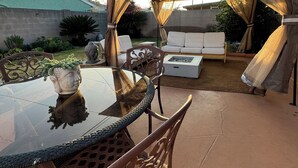 An outdoor patio area with a glass table, metal chairs, a cushioned sofa, and a canopy. - Buena Park Modern Home/Knott's/Disney/Beach

 (Buena Park)