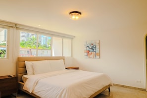 A bedroom with a bed, nightstand, and a painting on the wall.