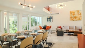 Un salon moderne avec un coin repas, de grandes fenêtres et un escalier.