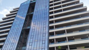 A modern multi-story building with reflective glass windows and a structured facade. - RT PROPERTIES AT KASS TOWERS  (Accra)