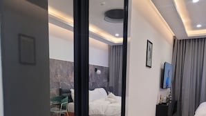 A modern hotel room with a large bed, a small seating area, and a television on the wall. - RT PROPERTIES AT KASS TOWERS  (Accra)