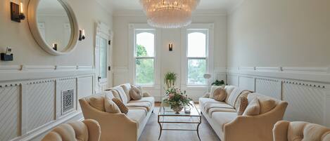A spacious living room with two sofas, a coffee table, and a large chandelier.