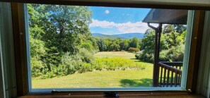 Enjoy a serene view from your deck overlooking a lush lawn and distant hills.