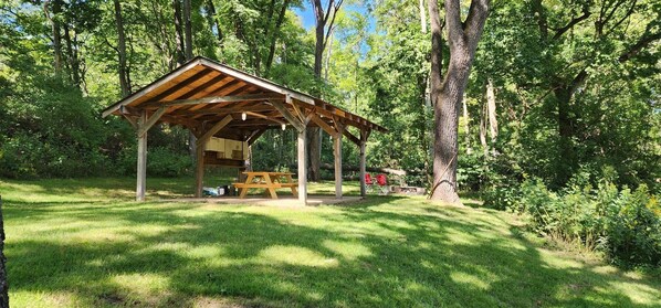 Situated in a lush forest, this pavilion offers a secluded space for outdoor dining or relaxation.