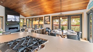 Une cuisine moderne dotée d’un grand îlot central, d’une cuisinière encastrée et d’un téléviseur à écran plat fixé au mur.