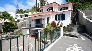 Un bâtiment blanc avec des toits recouverts de tuiles rouges, un balcon et un escalier en pierre.