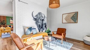 A modern living room with a white brick wall, a large bull mural, a wooden bench, leather chairs, a coffee table, and a geometric rug. - Mountain Views ~Climbing wall ~Mini Golf ~Hot tub (Colorado Springs)