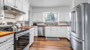 A modern kitchen with white cabinets, stainless steel appliances, and a wooden countertop. - Mountain Views ~Climbing wall ~Mini Golf ~Hot tub (Colorado Springs)