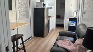 Um espaço compacto com cozinha compacta, cama, área de estar com manta e uma pequena mesa.