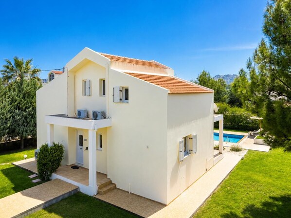 A two-story house with a swimming pool, a covered patio, and a well-maintained lawn. - Villa Apollo Classico (Kolympia)