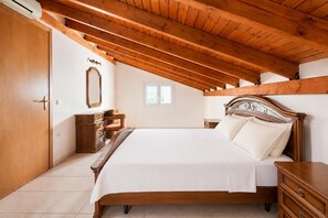 Een slaapkamer met een houten bed, een dressoir, een nachtkastje, een spiegel en een raam.