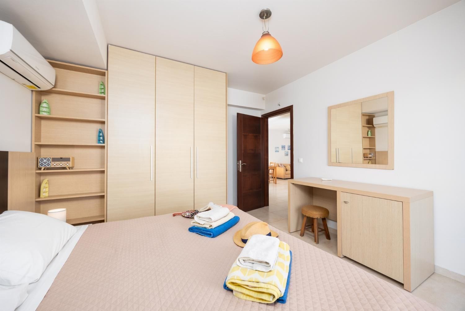 Et moderne soveværelse med seng, skrivebord, garderobe og spejl.