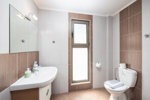 Un bagno moderno con lavandino, specchio, servizi igienici e una finestra.