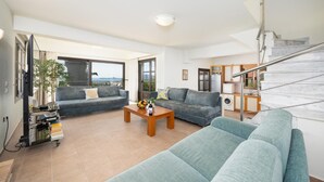 Ein modernes Wohnzimmer mit einer Sofagarnitur, einem Couchtisch und einem Fernseher.