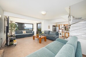 Ein modernes Wohnzimmer mit einer Sofagarnitur, einem Couchtisch und einem Fernseher.