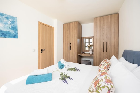 Une chambre à coucher avec un lit, une armoire, un miroir et un tableau accroché au mur.
