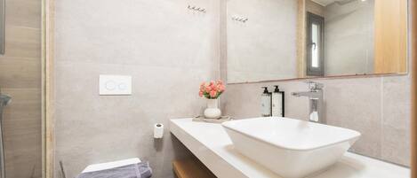 A modern bathroom with a white sink, a mirror, and a toilet.