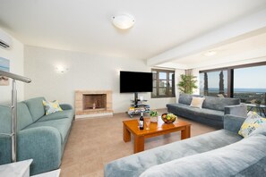 Ein modernes Wohnzimmer mit Kamin, Flachbildfernseher und einem Balkon mit Blick.
