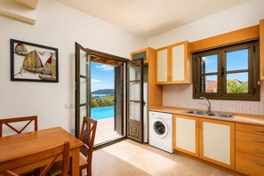 A kitchen with a view of a swimming pool, a washing machine, and a dining area with a table and chairs.