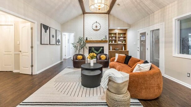 A spacious living room with a fireplace, a round coffee table, a sofa, and a bookshelf. - Serenity WR Deluxe Escape Indoor Pool (Warner Robins)