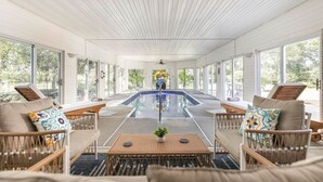 A pool area with lounge chairs, a table, and a ceiling fan. - Serenity WR Deluxe Escape Indoor Pool (Warner Robins)