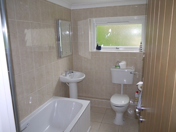 Un baño con bañera, lavamanos, inodoro y ventana.
