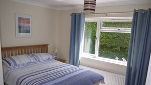 Un dormitorio con una cama, una ventana con cortinas, un radiador y una lámpara de pared.