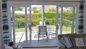 Un salón acogedor con un sofá y una mesa con sillas, una puerta corrediza de vidrio que da a un patio exterior con una mesa y sillas.