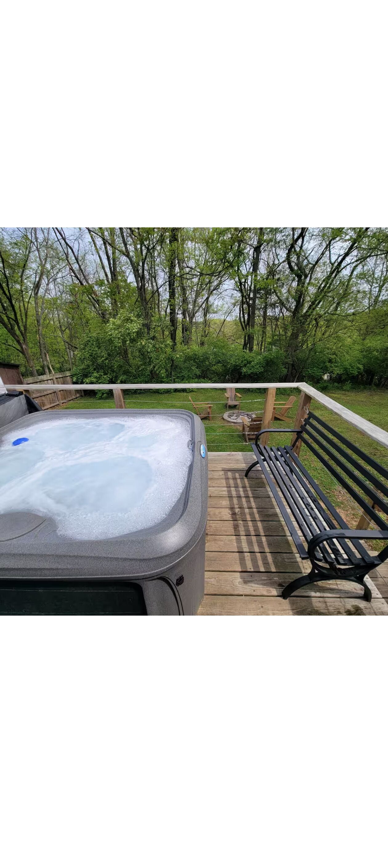 Un jacuzzi en una terraza de madera con un banco y una valla.