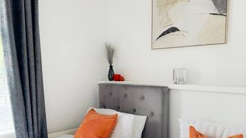 A hotel room with two beds, a grey headboard, and a painting on the wall.