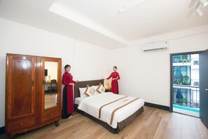 A hotel room with a wooden wardrobe, a bed with a white and brown bedspread, and a view of a balcony through an open door. - The Rice Hotel & Tour - 131 Bui Vien (Ho Chi Minh City)