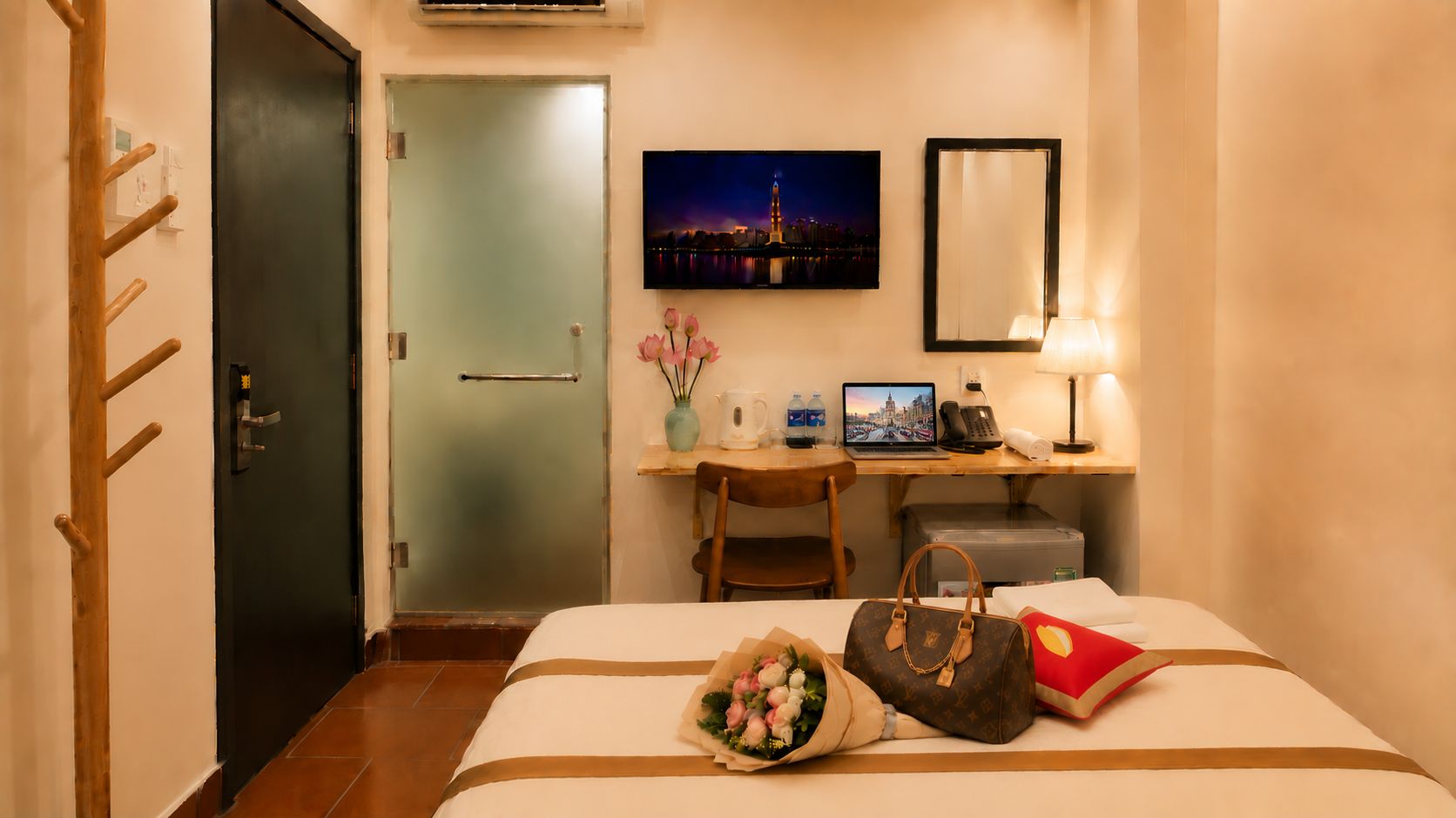 Habitación de hotel con cama, escritorio con una computadora portátil, espejo y una pintura con vista nocturna.