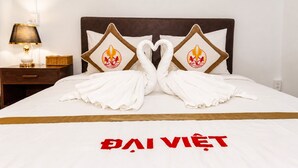 A bed with towels arranged in swan shapes and a bedspread with 'DAI VIET' text. - The Rice Hotel & Tour - 131 Bui Vien (Ho Chi Minh City)
