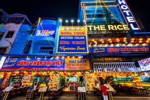 A brightly lit restaurant with multiple signs advertising Western-Italian, Mexican, Vietnamese, and vegetarian foods. - The Rice Hotel & Tour - 131 Bui Vien (Ho Chi Minh City)