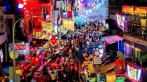 Une rue animée, bondée de monde, avec de nombreuses enseignes lumineuses.