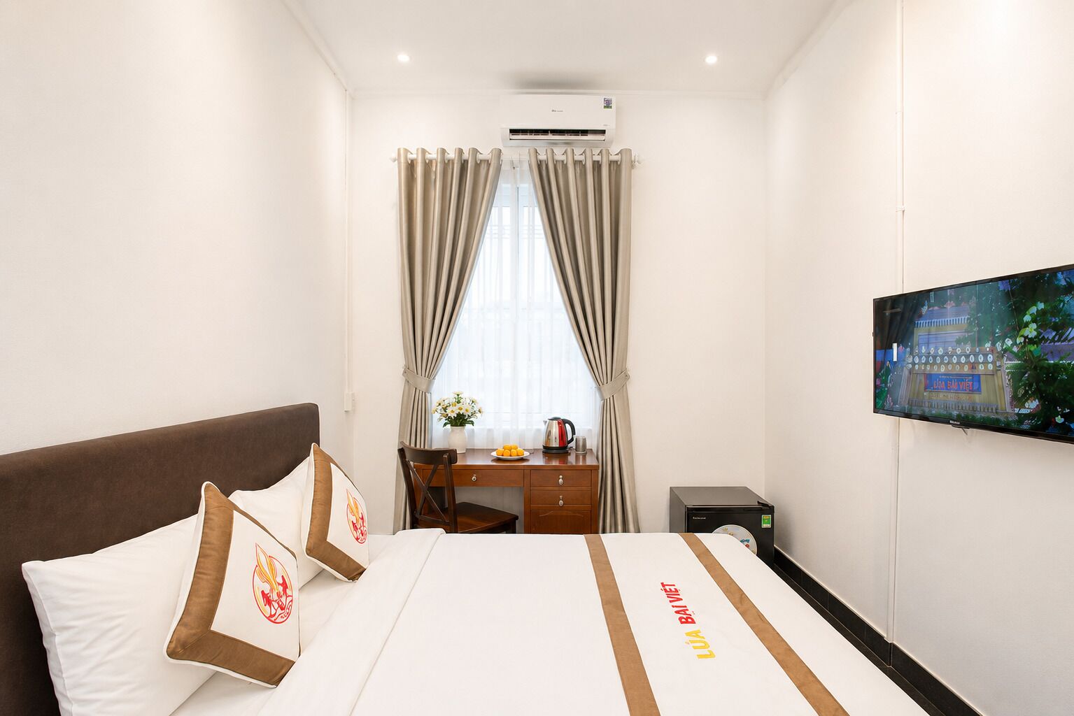 Una habitación de hotel con cama, escritorio, televisor y aire acondicionado.