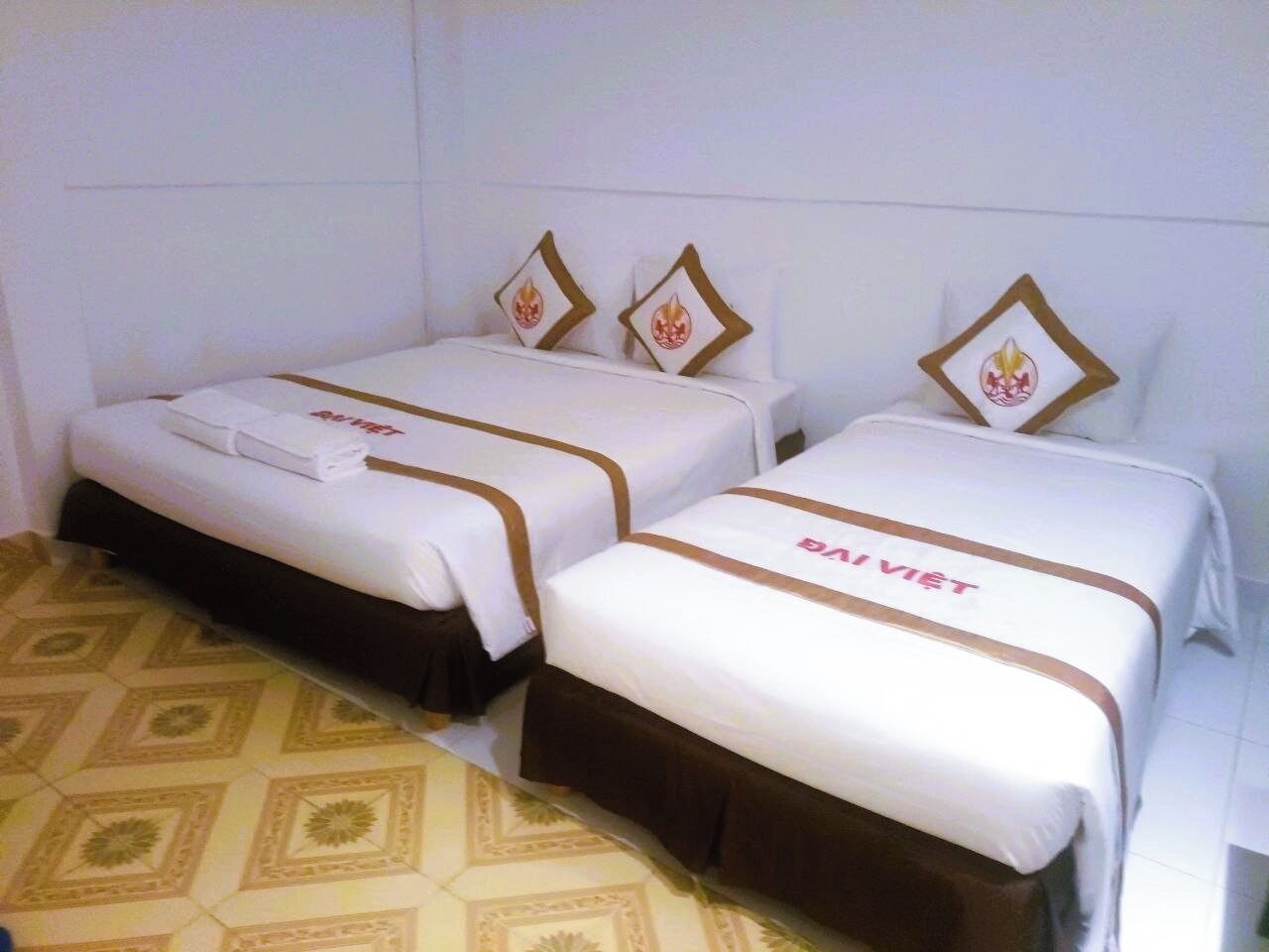 Dos camas individuales con cabeceras y pies de cama a juego, un suelo estampado y una pared blanca.