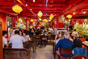 A bustling restaurant with wooden furniture and red decor. - The Rice Hotel & Tour - 131 Bui Vien (Ho Chi Minh City)