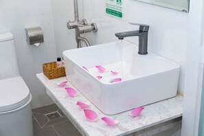 A bathroom with a white sink, a towel dispenser, and a trash bin. - The Rice Hotel & Tour - 131 Bui Vien (Ho Chi Minh City)
