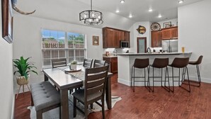 Una cocina moderna con armarios de madera, una isla central con taburetes y un comedor con mesa y sillas.