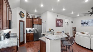 Una cocina moderna con armarios de madera, un refrigerador de acero inoxidable y una isla de mármol.