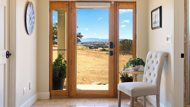 A room with a sliding glass door leading to a view of a dry landscape with mountains.