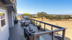 A wooden deck with outdoor furniture, a table, and a green umbrella.