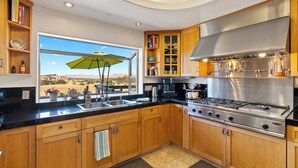 A modern kitchen with wooden cabinets, a large window, and a view of the desert.
