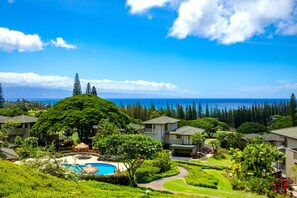 A resort with a swimming pool, lush greenery, and ocean views.