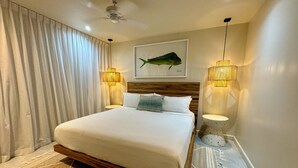 A modern bedroom with a large bed, two bedside lamps, a ceiling fan, and a fish painting on the wall. - Boho House: Tamarindo Beach (Tamarindo)