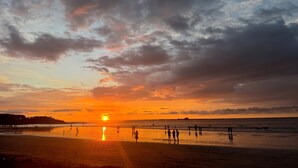 A beach at sunset with people walking and playing in the sand. - Boho House: Tamarindo Beach (Tamarindo)