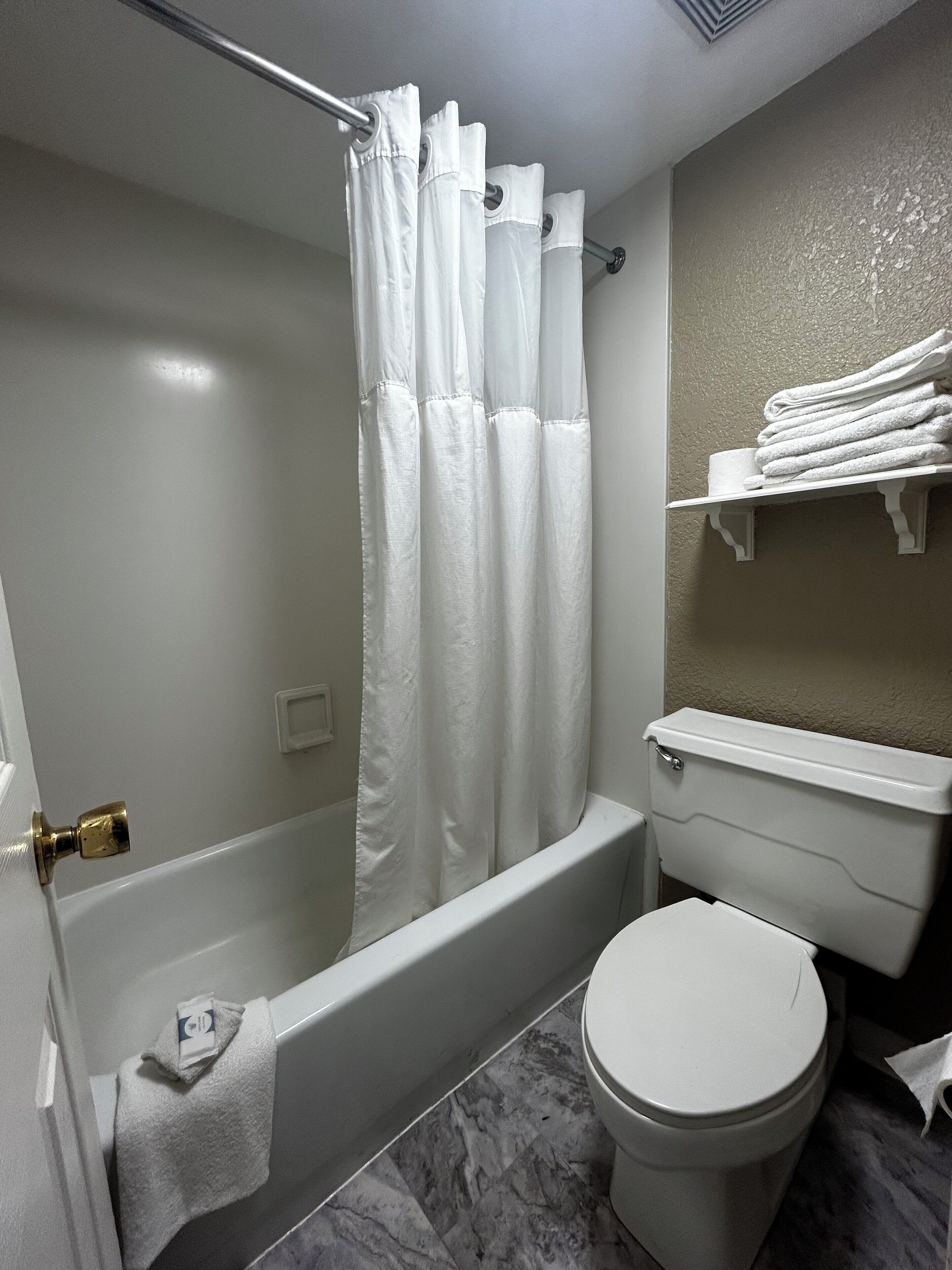 A bathroom with a bathtub, toilet, and a towel rack.