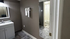 A bathroom with a marble floor, a white sink, and a large mirror.